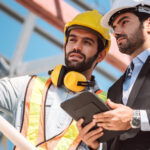 Civil engineer and construction worker manager holding digital tablet and blueprints , talking and planing about construction site.  Cooperation teamwork concept.